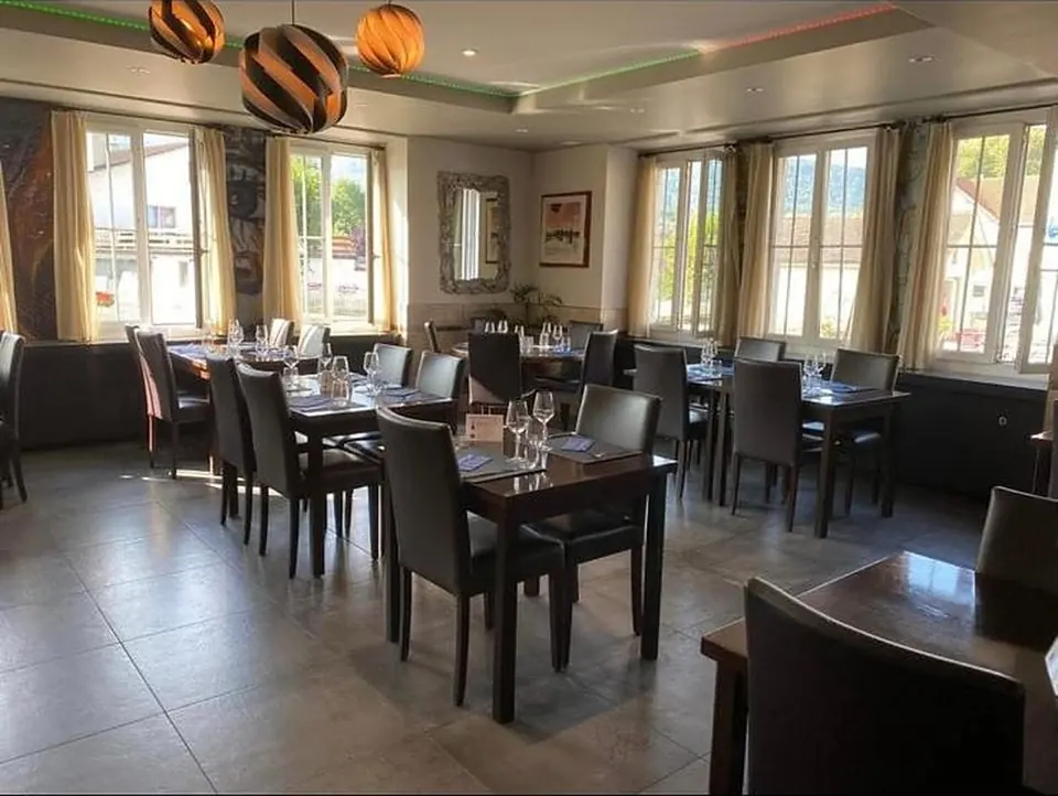 La grande salle de La Nuova Corona de jour : tables dressées devant les fenêtres.
